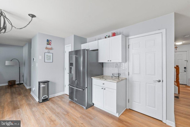 kitchen featuring light hardwood / wood-style floors, white cabinetry, high end refrigerator, and light stone counters