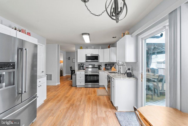 kitchen with white cabinetry, stainless steel appliances, sink, light wood-type flooring, and light stone counters