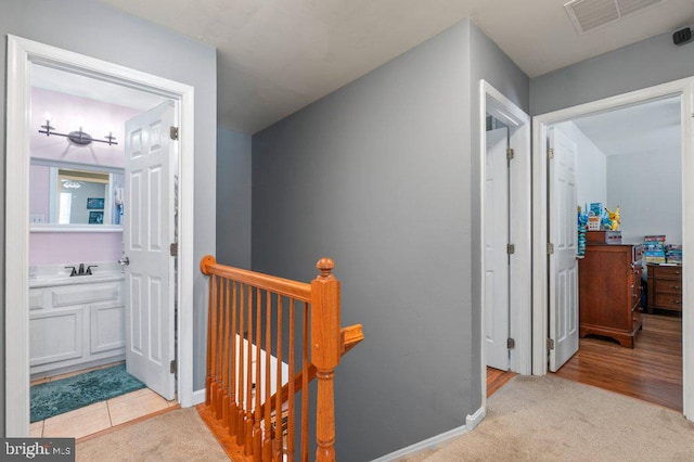 corridor with light colored carpet and sink