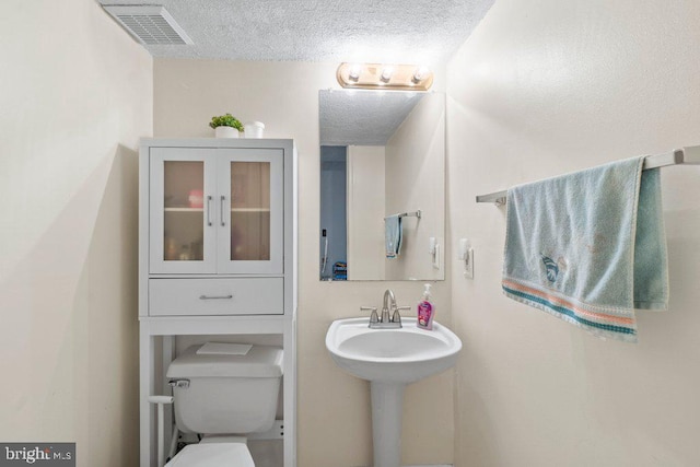 bathroom with toilet and a textured ceiling