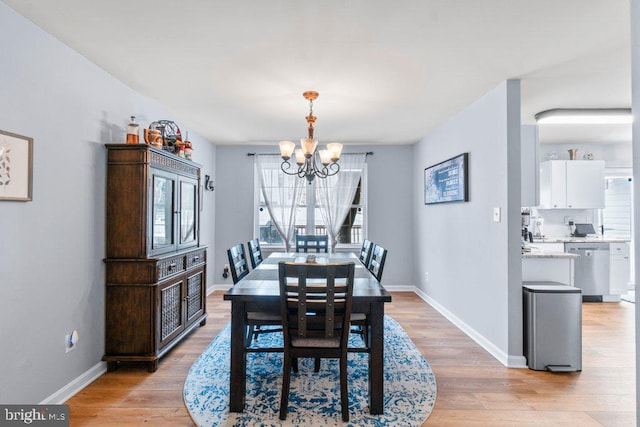 dining area with light hardwood / wood-style flooring and an inviting chandelier