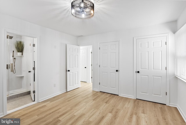 unfurnished bedroom featuring ensuite bathroom and light wood-type flooring