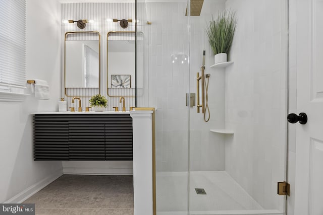 bathroom featuring double vanity, a stall shower, baseboards, and a sink