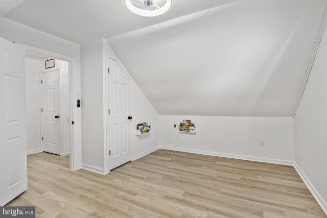 bonus room with light wood finished floors, baseboards, and vaulted ceiling