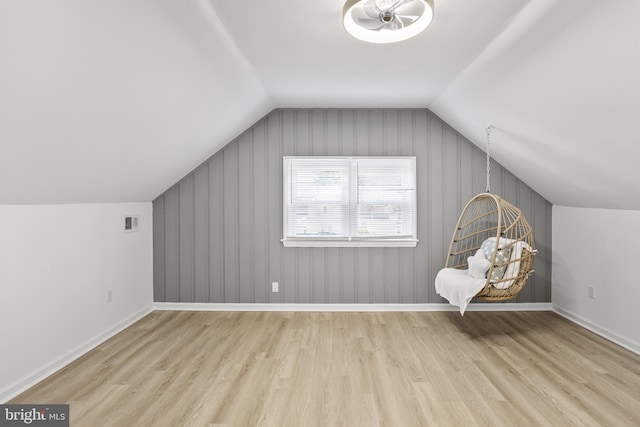 bonus room featuring lofted ceiling, visible vents, baseboards, and wood finished floors