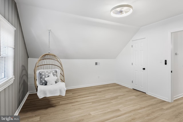 unfurnished room featuring light wood-style flooring, visible vents, vaulted ceiling, and baseboards