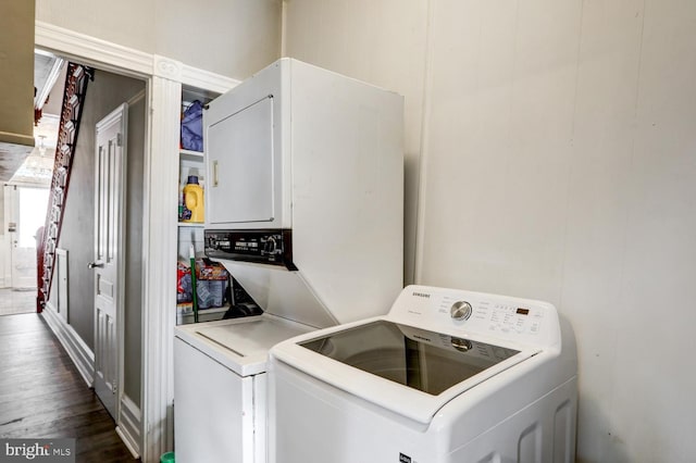 clothes washing area featuring stacked washing maching and dryer and dark wood-type flooring