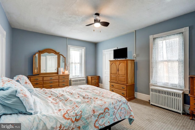 carpeted bedroom with radiator, ceiling fan, and multiple windows