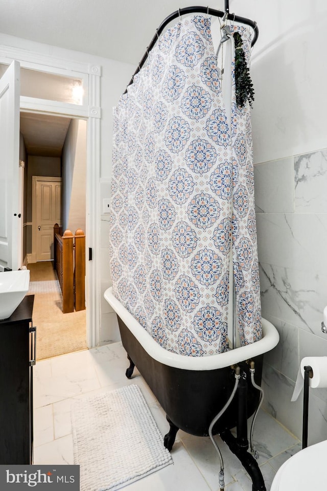 bathroom featuring vanity, a bath, and tile walls