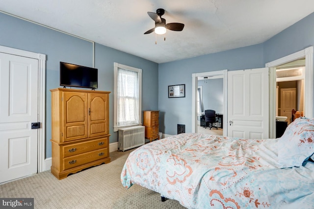 bedroom featuring radiator, ceiling fan, ensuite bathroom, and light carpet