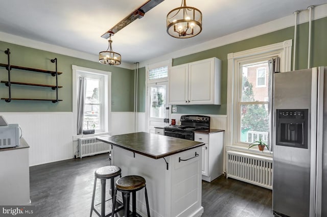 kitchen with a notable chandelier, stainless steel fridge, white cabinetry, and radiator