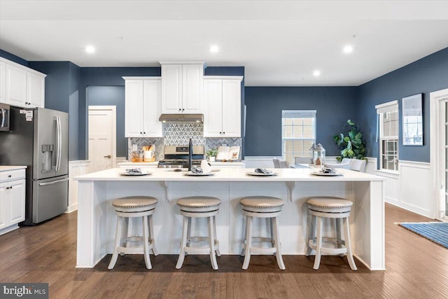 kitchen with white cabinets, a breakfast bar, stainless steel appliances, and a center island with sink