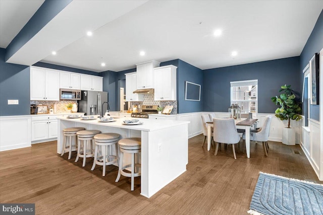 kitchen featuring stainless steel appliances, light hardwood / wood-style floors, white cabinets, and a large island