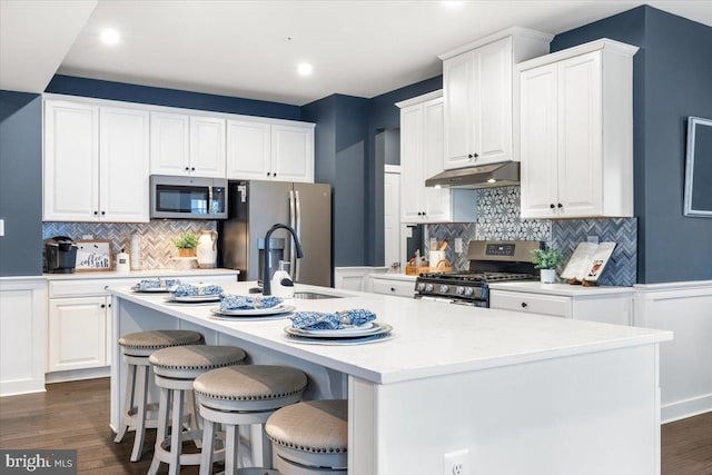 kitchen with white cabinets, appliances with stainless steel finishes, and an island with sink