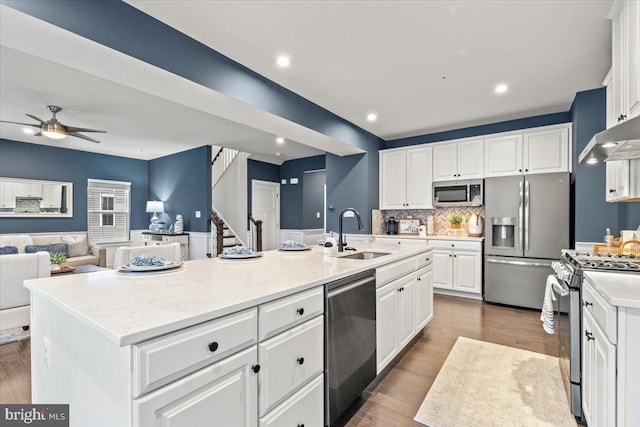 kitchen featuring backsplash, sink, white cabinetry, a kitchen island with sink, and appliances with stainless steel finishes