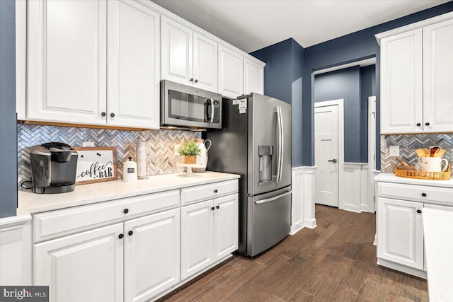 kitchen with white cabinets, appliances with stainless steel finishes, and dark hardwood / wood-style flooring