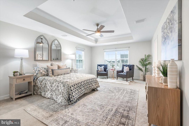 carpeted bedroom with ceiling fan and a raised ceiling