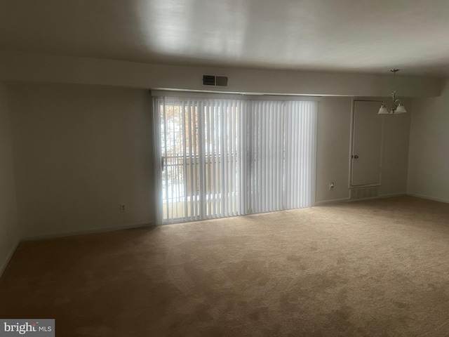 empty room with carpet floors and an inviting chandelier