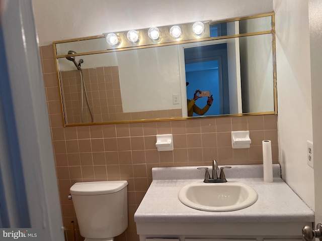 bathroom with tile walls, toilet, and vanity