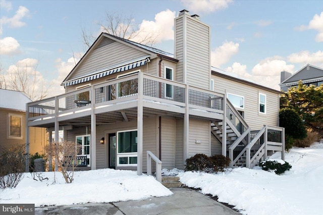 snow covered house featuring a wooden deck