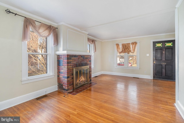 living room featuring light hardwood / wood-style floors, ornamental molding, and a brick fireplace