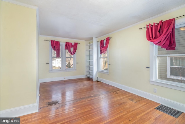 spare room featuring hardwood / wood-style floors, built in features, and ornamental molding