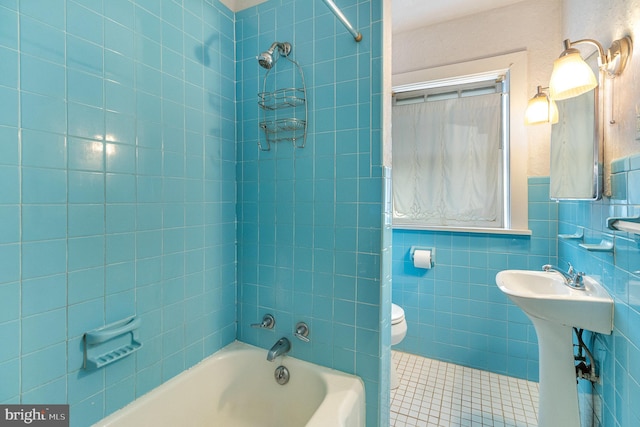 bathroom featuring tiled shower / bath, toilet, tile walls, and tile patterned floors