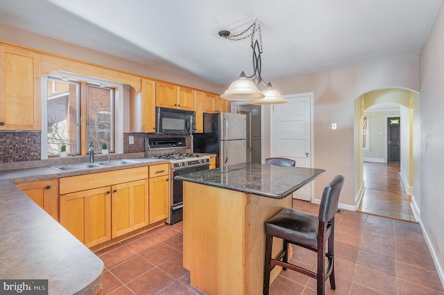 kitchen featuring a kitchen island, light brown cabinetry, and gas range