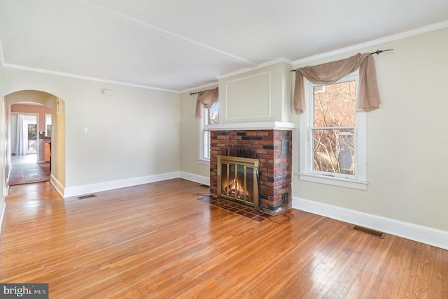 unfurnished living room with crown molding, a fireplace, and light wood-type flooring