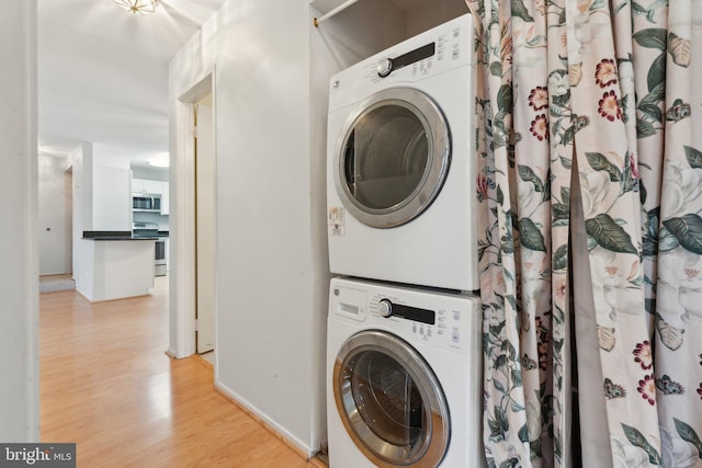 washroom with stacked washer / dryer and light hardwood / wood-style floors