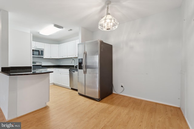 kitchen featuring appliances with stainless steel finishes, decorative light fixtures, light wood-type flooring, and white cabinets