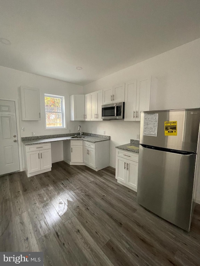 kitchen with white cabinetry, dark wood-type flooring, stainless steel appliances, and sink