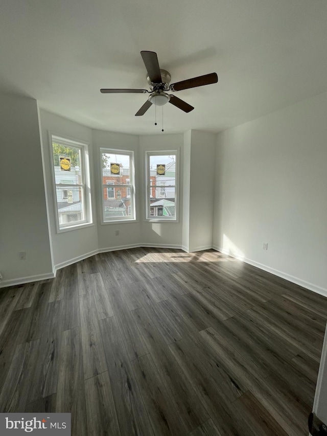 spare room featuring dark hardwood / wood-style flooring, ceiling fan, and a healthy amount of sunlight