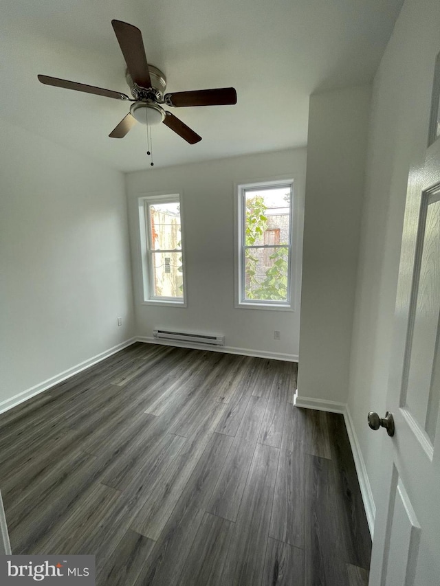 empty room featuring ceiling fan, dark wood-type flooring, and a baseboard heating unit