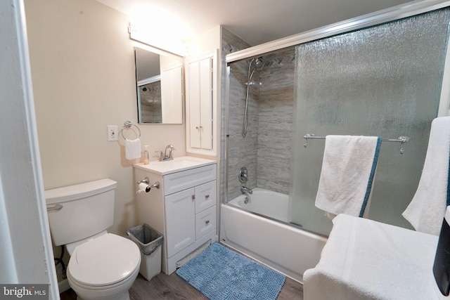 full bathroom featuring toilet, vanity, bath / shower combo with glass door, and hardwood / wood-style flooring