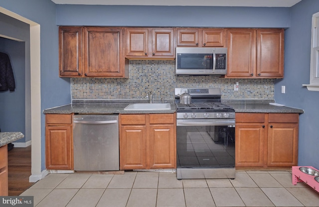 kitchen featuring decorative backsplash, appliances with stainless steel finishes, light tile patterned floors, and sink