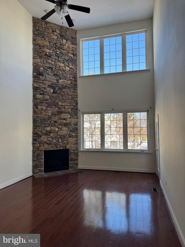 unfurnished living room featuring ceiling fan, dark wood-type flooring, and a fireplace