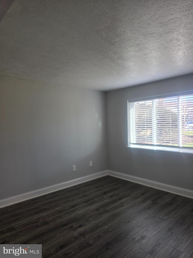 empty room featuring a textured ceiling and dark hardwood / wood-style flooring