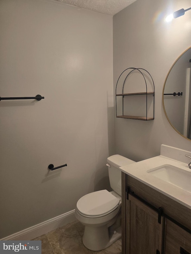 bathroom featuring vanity, a textured ceiling, toilet, and tile patterned flooring