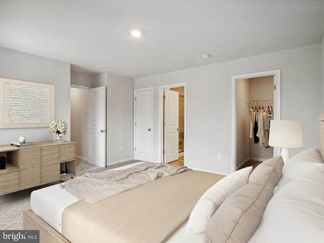 bedroom featuring light carpet, a walk in closet, ensuite bath, and a closet