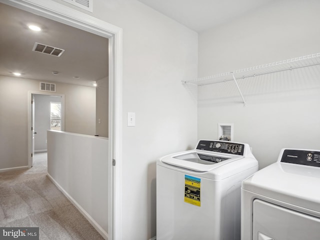 laundry room with washing machine and dryer and light colored carpet