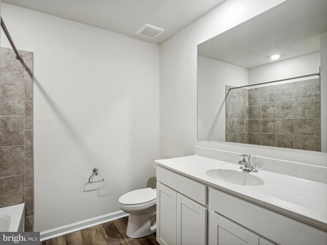 full bathroom with hardwood / wood-style floors, vanity, toilet, and tiled shower / bath