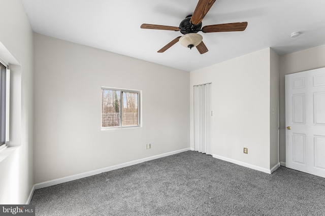 spare room featuring dark colored carpet and ceiling fan