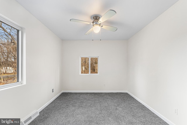 spare room featuring ceiling fan and dark carpet