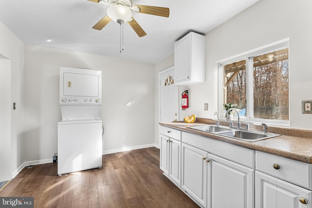 kitchen with ceiling fan, sink, white cabinets, dark hardwood / wood-style floors, and stacked washer / drying machine