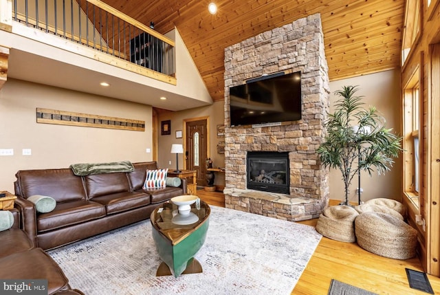 living room with a fireplace, a towering ceiling, hardwood / wood-style flooring, and wood ceiling