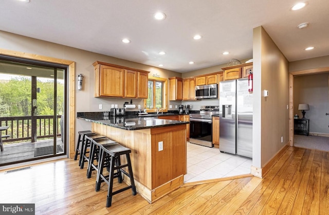 kitchen with plenty of natural light, kitchen peninsula, stainless steel appliances, and light hardwood / wood-style flooring