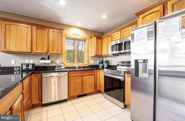 kitchen featuring light tile patterned flooring, appliances with stainless steel finishes, dark stone counters, and sink