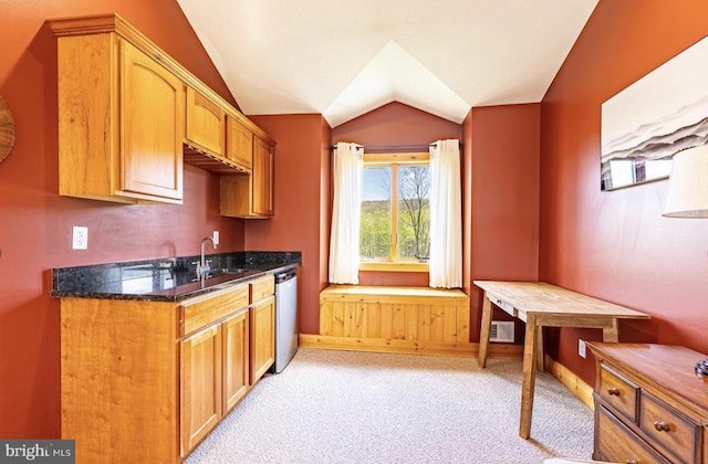 kitchen featuring sink, vaulted ceiling, stainless steel dishwasher, dark stone countertops, and light colored carpet