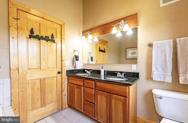 bathroom with toilet, vanity, and tile patterned floors